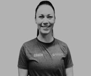 kvindelig fitness intruktør i en T-shirt påført skriften "Keep Fit Coach" smiler ind i kameraet