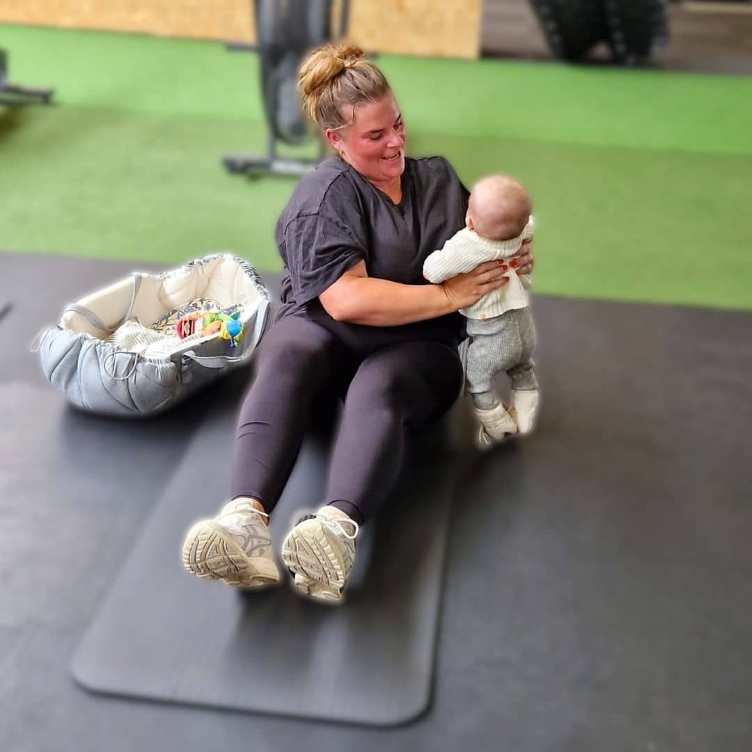 Nybagt mor holder sin baby i armene under en MomWOD i Keep Fit i Nørresundby